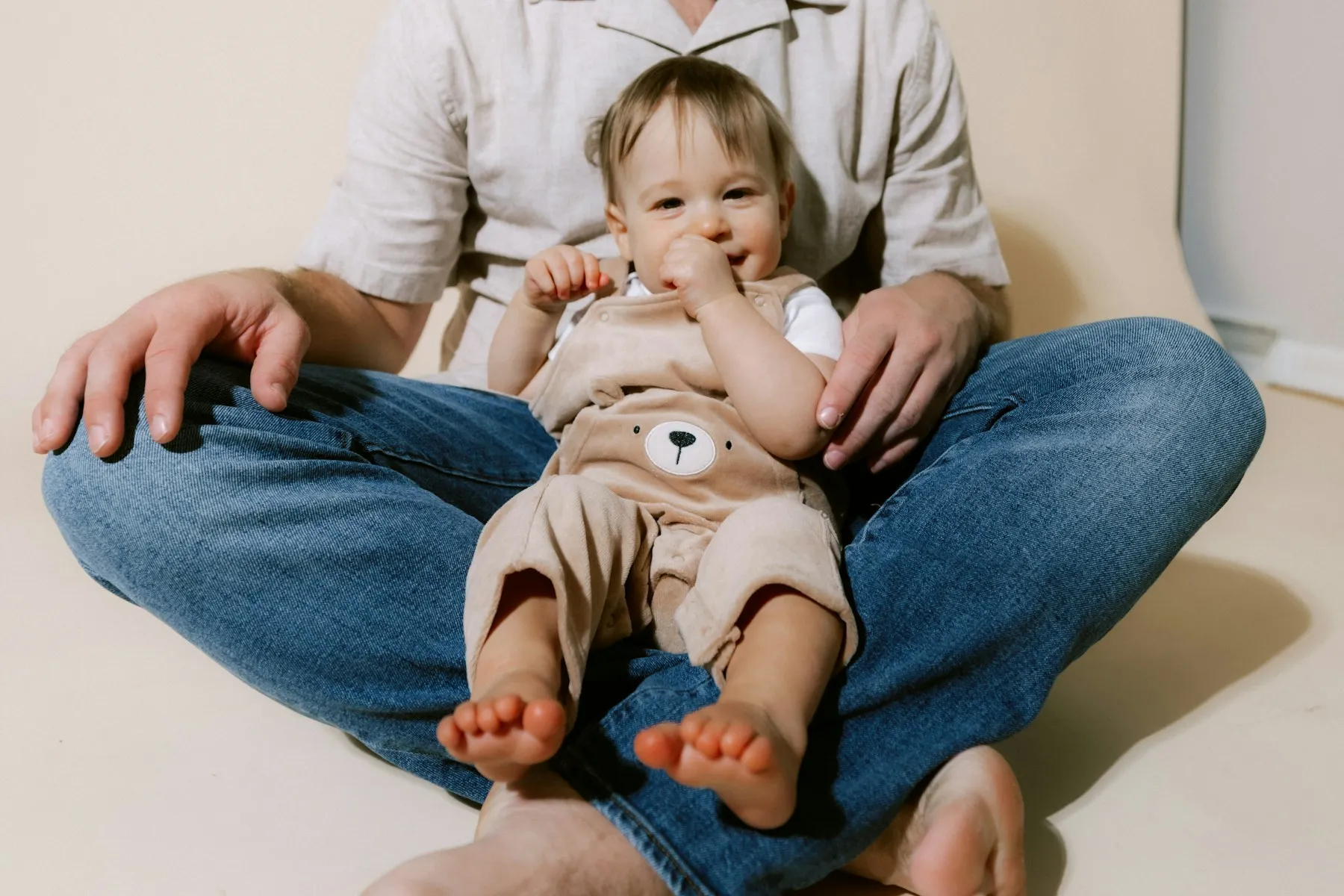 A smiling baby sitting on a parent's lap