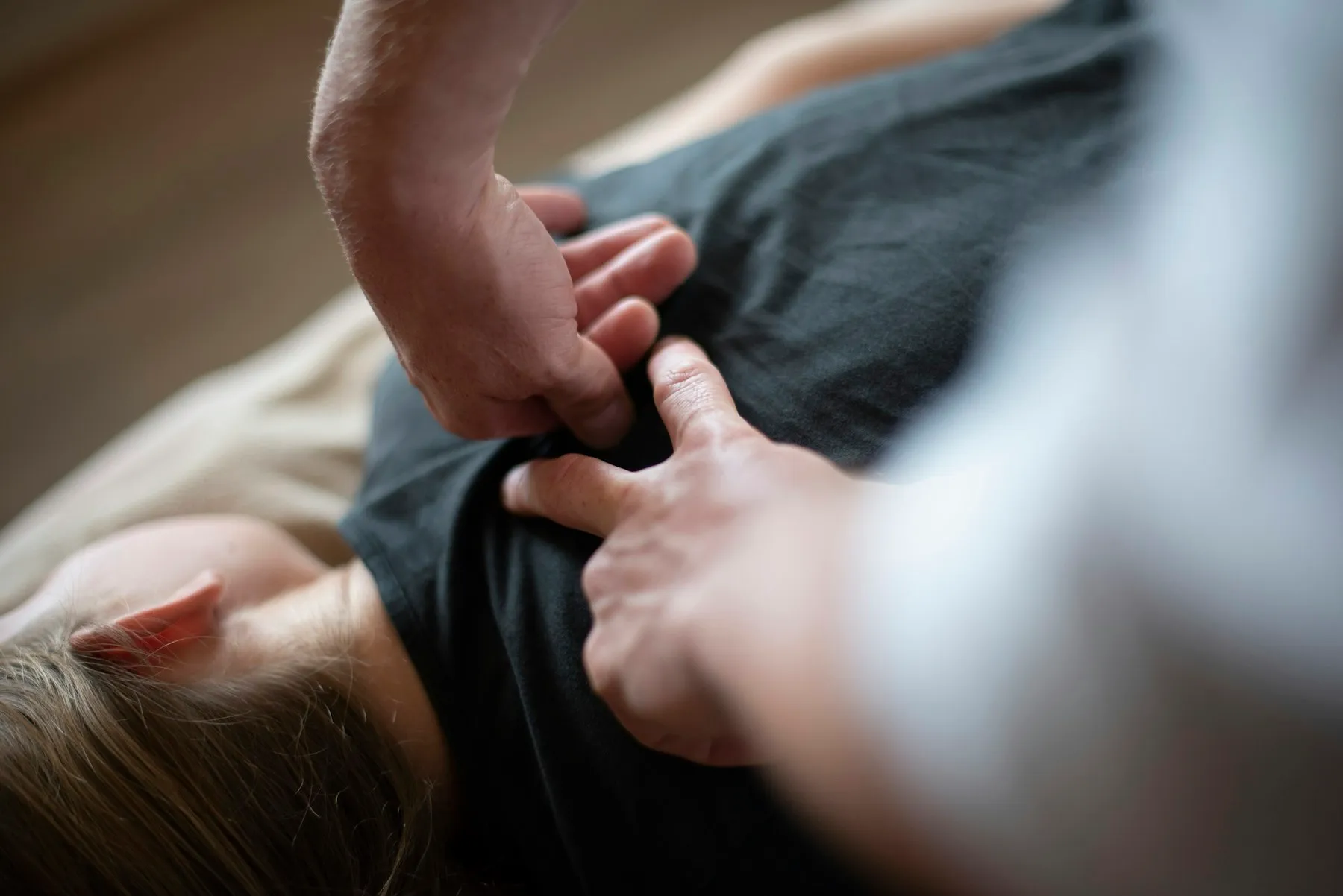 Hands working on the upper back of a patient lying face down
