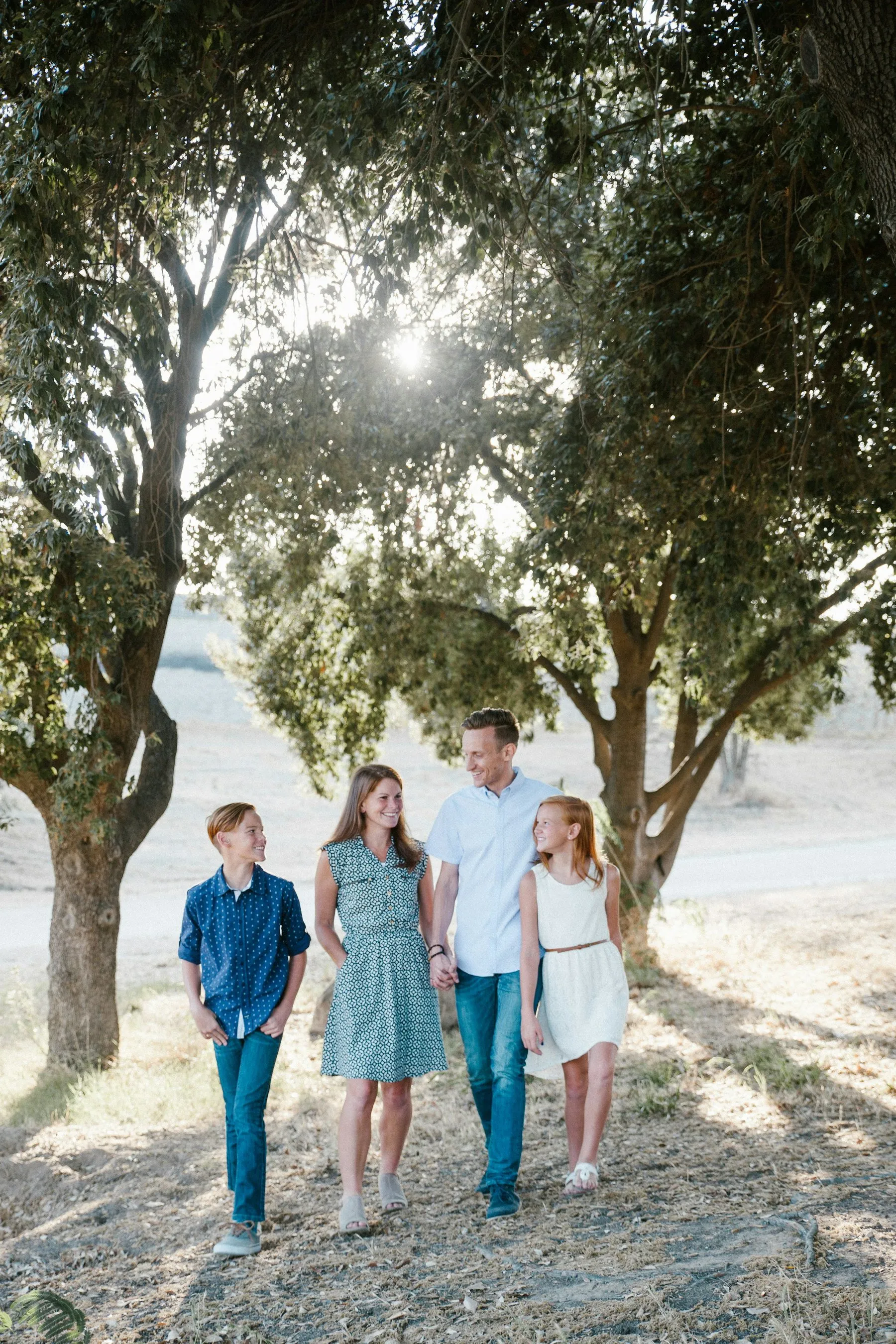 A family of four walking towards the door under shady trees