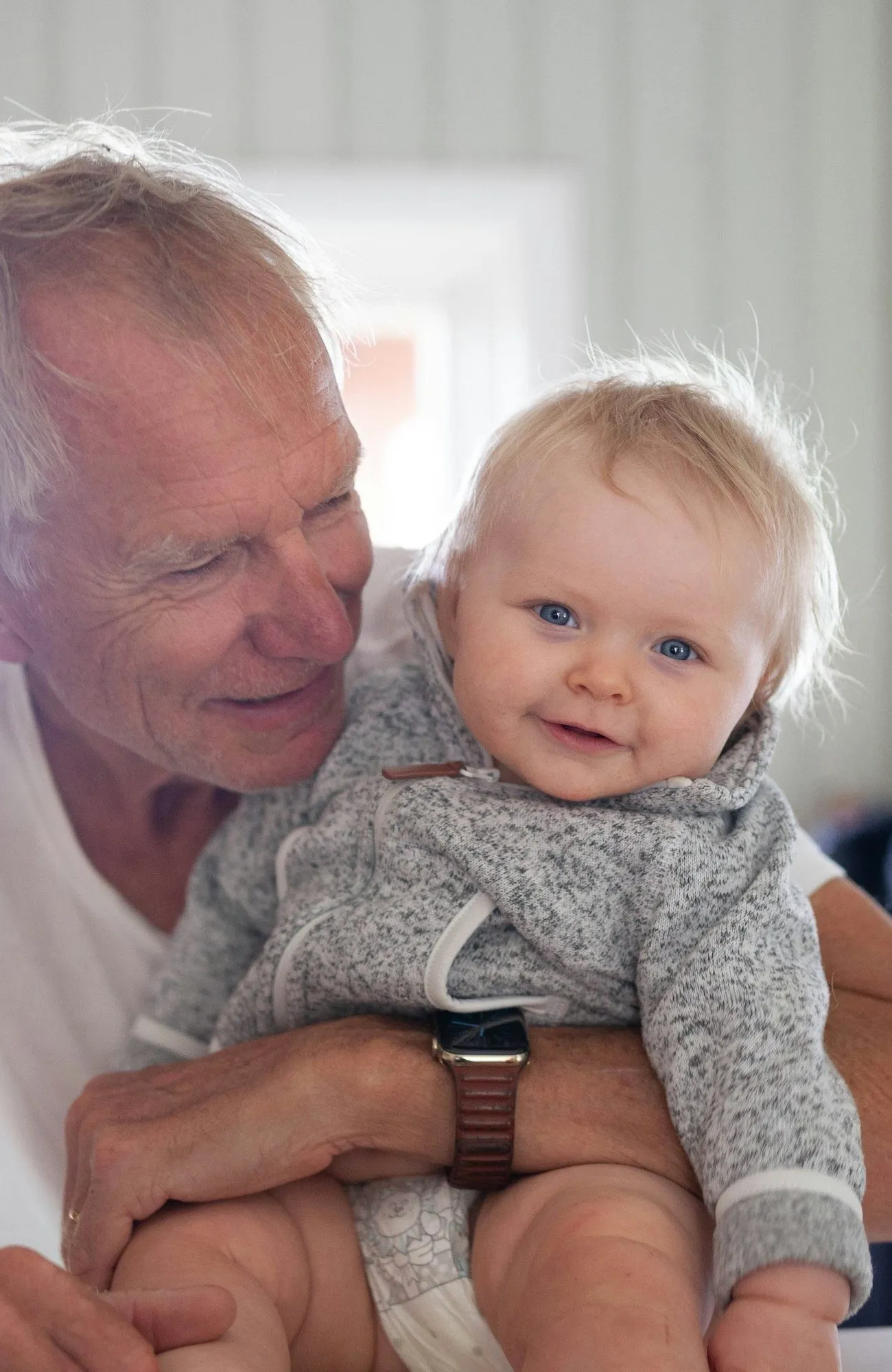 A grandfather laughing with his baby grandchild at home
