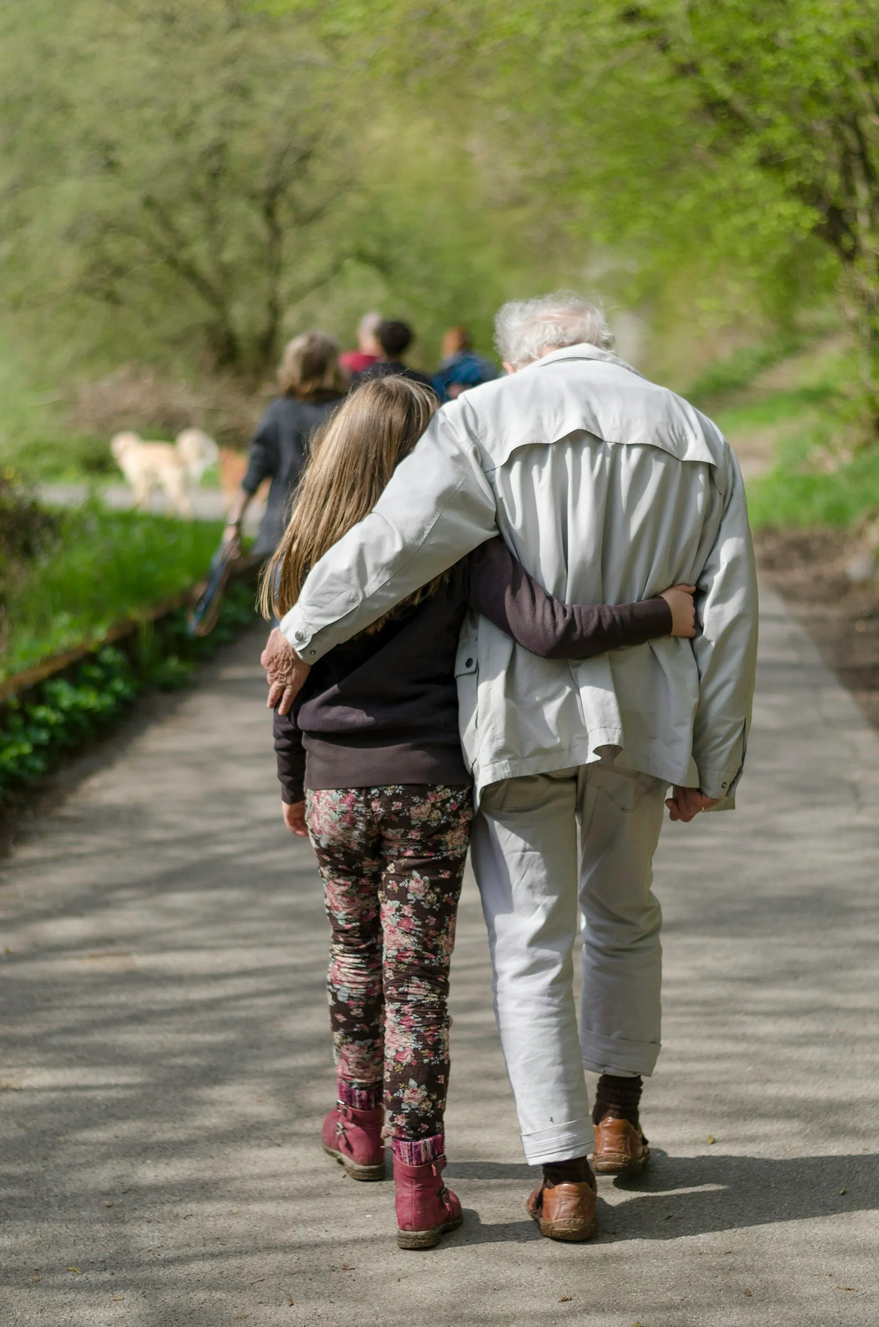 An older couple walking arm in arm along a path